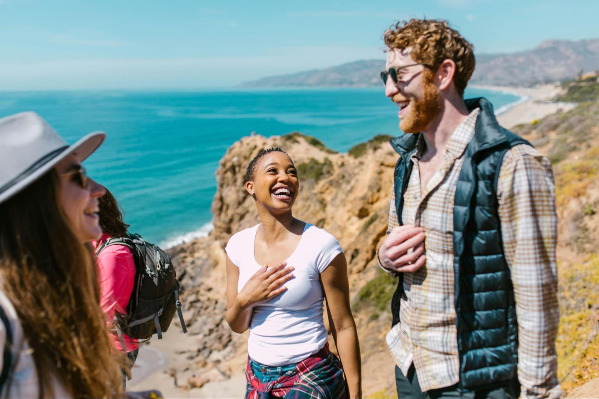 A group of friends laughing together on a sunny beach