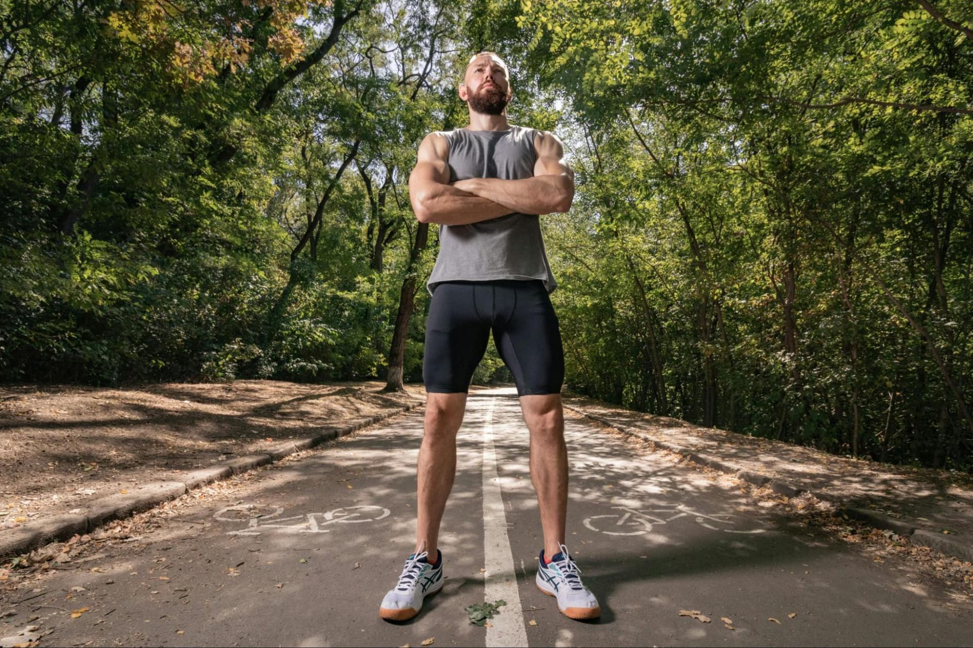 A man in workout clothes standing on a running trail in woods