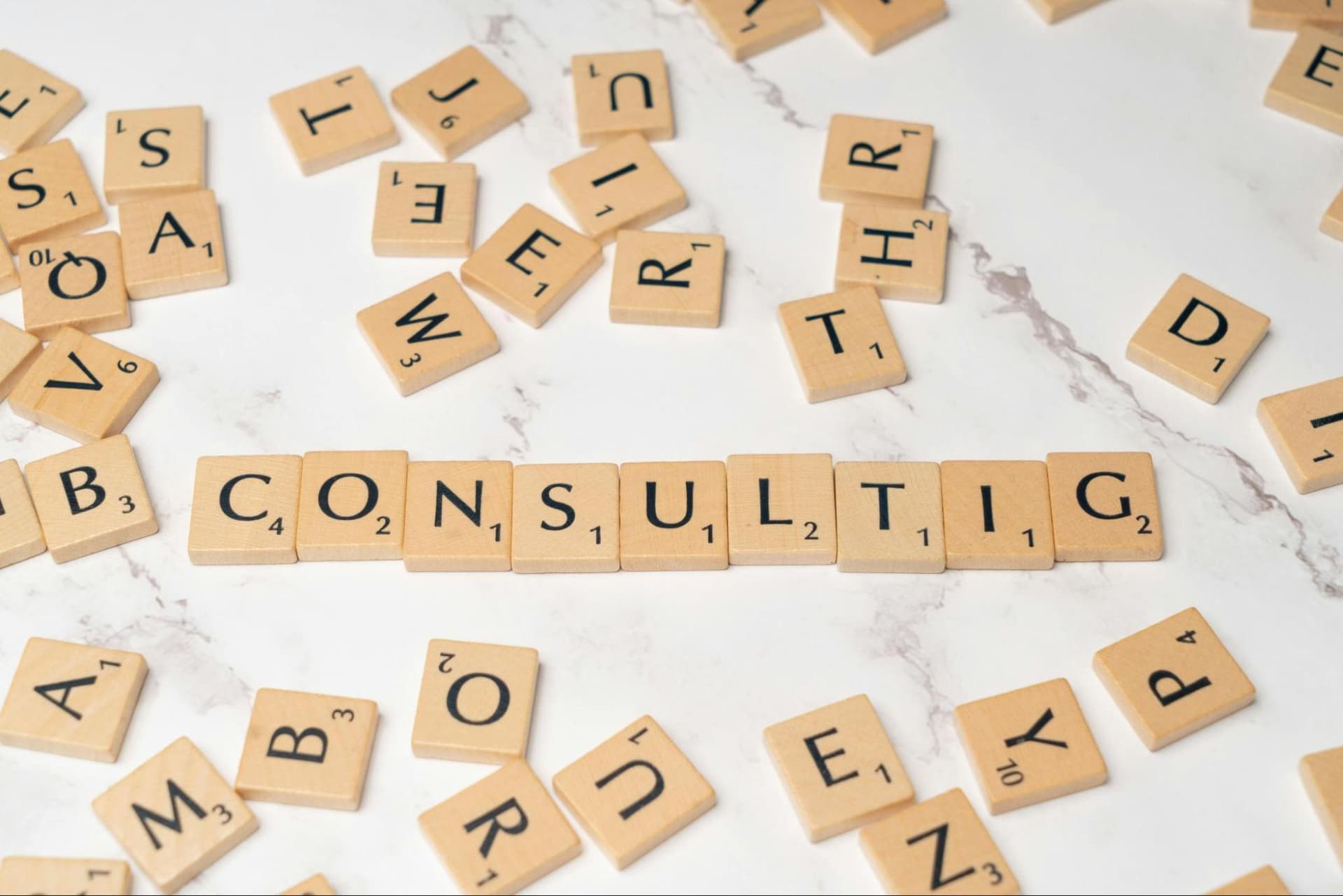 Small wooden letter blocks arranged to spell “consulting,” surrounded by random scattered letters