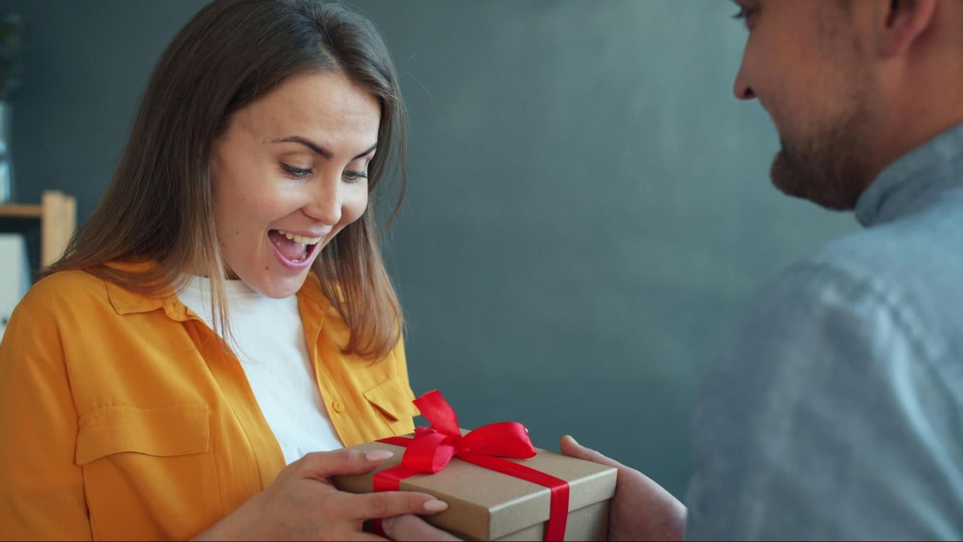 Woman smiling as she receives a gift from a man