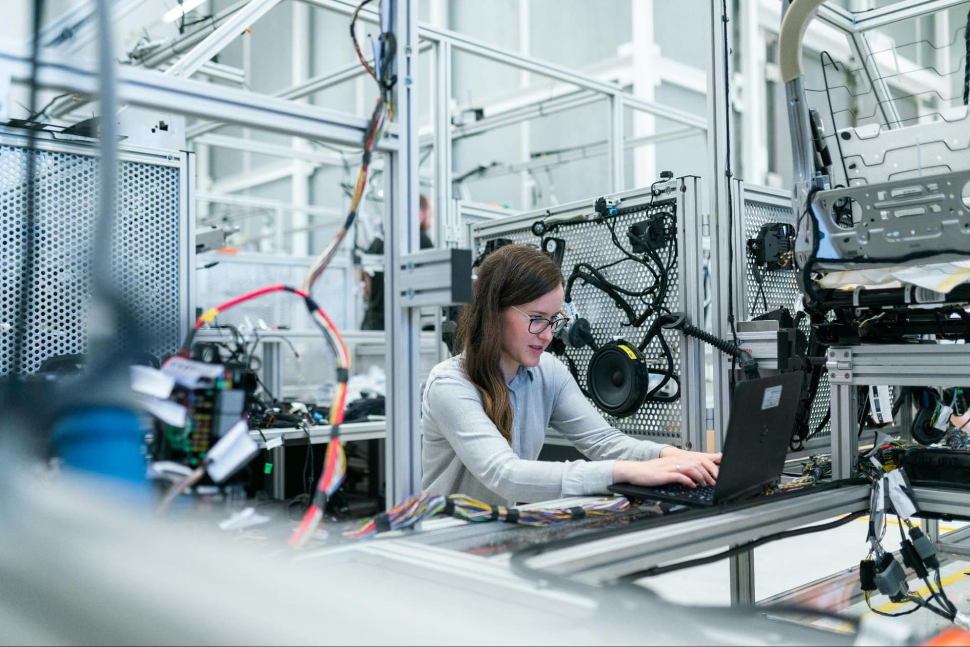 A woman working on a laptop in an electronics lab environment