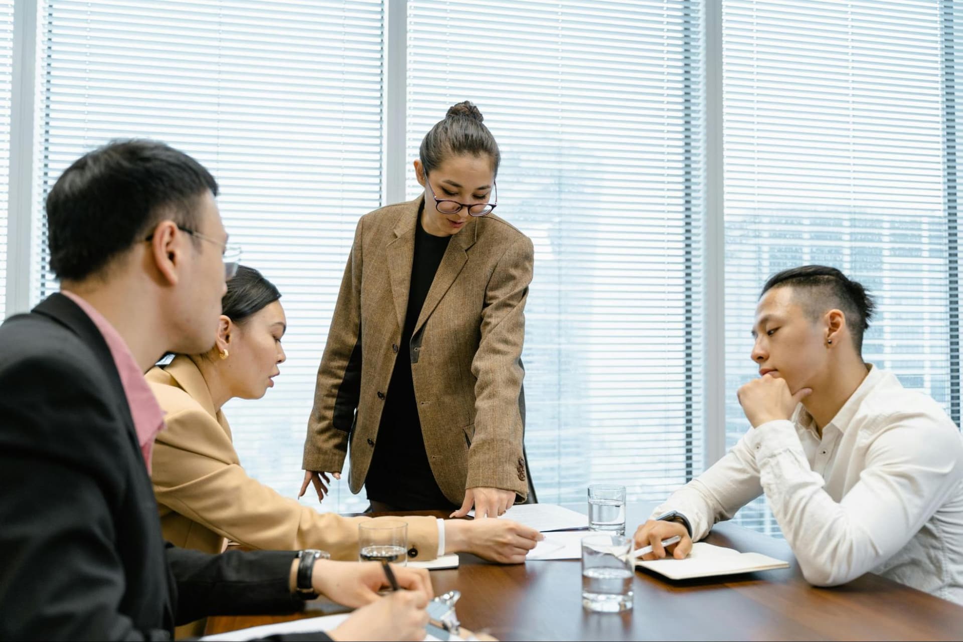 Four colleagues at a corporate office discussing something at a desk