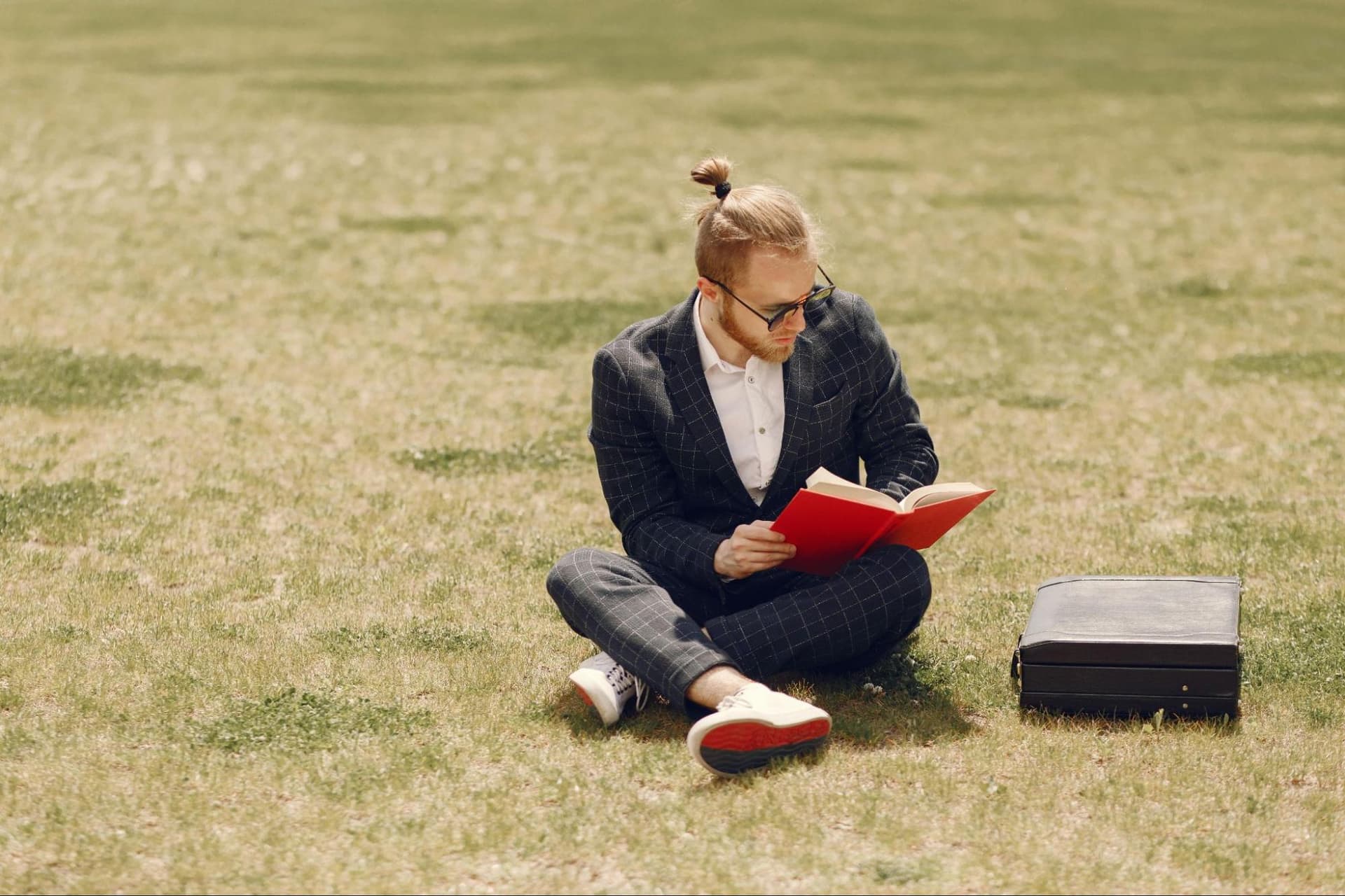 A man sitting on grass and reading a book