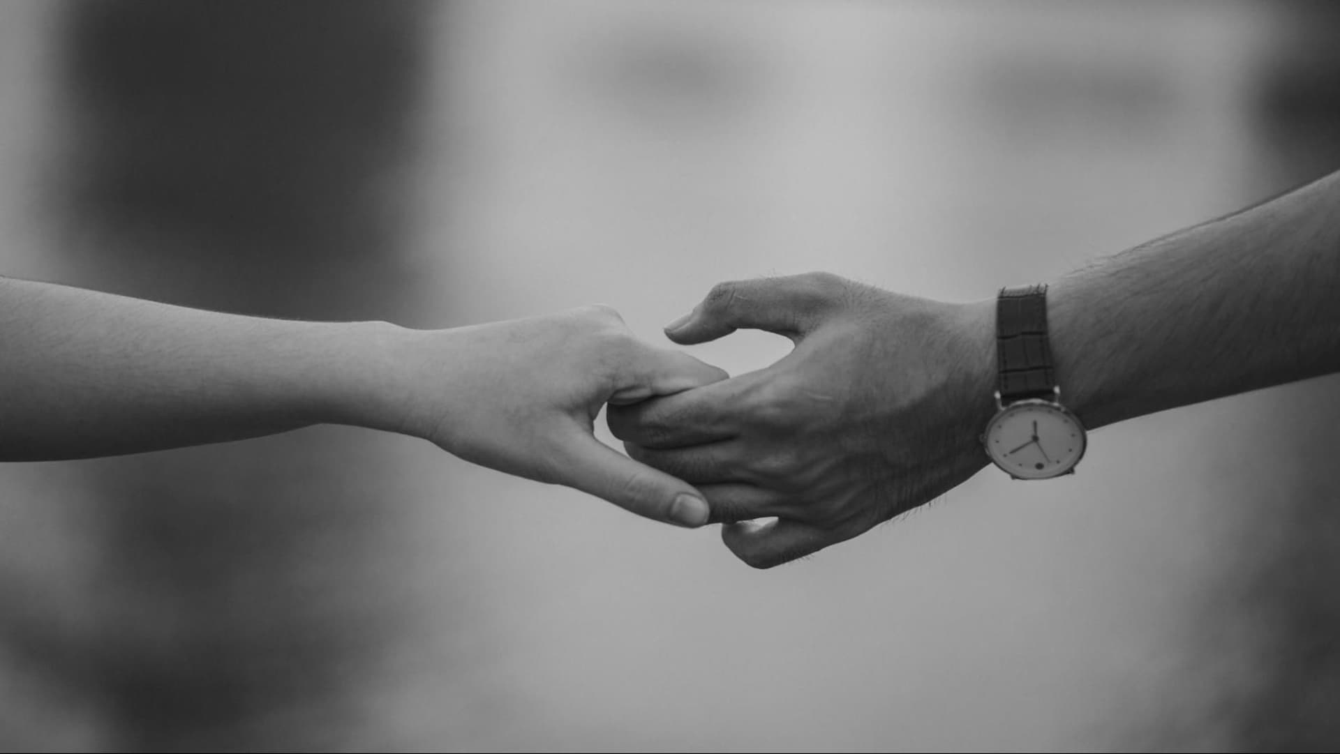 Black and white close-up of two people holding hands