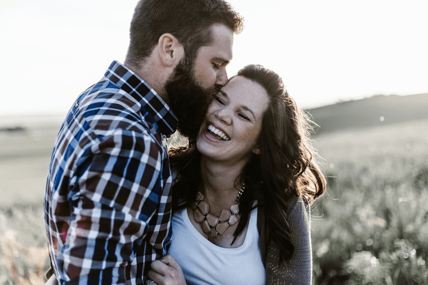A man kissing a woman while she's smiling, indicating a romantic relationship