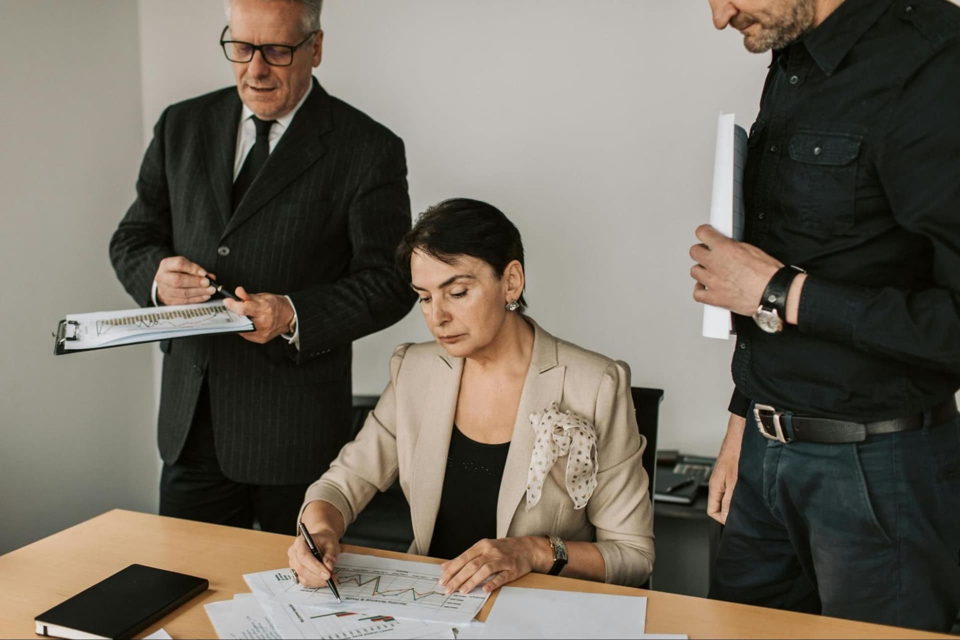 Three businesss people looking at documents with charts