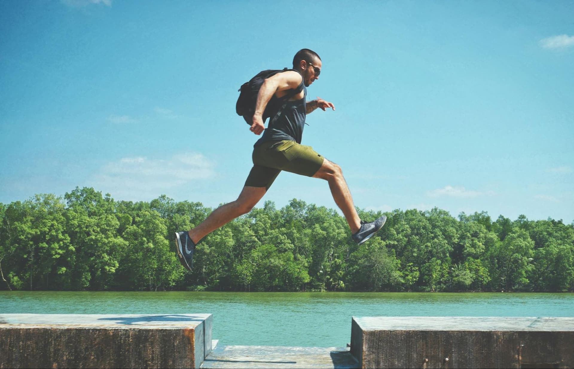 A man jumping from one concrete block to another with woods in the background