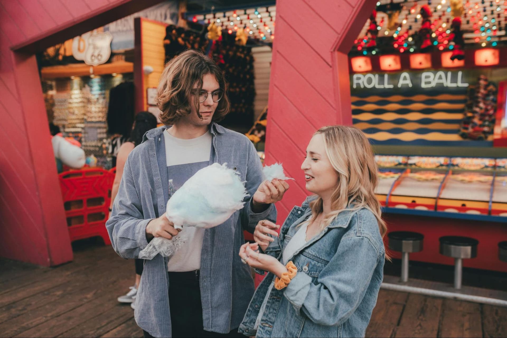 A young man and a woman sharing cotton candy at a fair