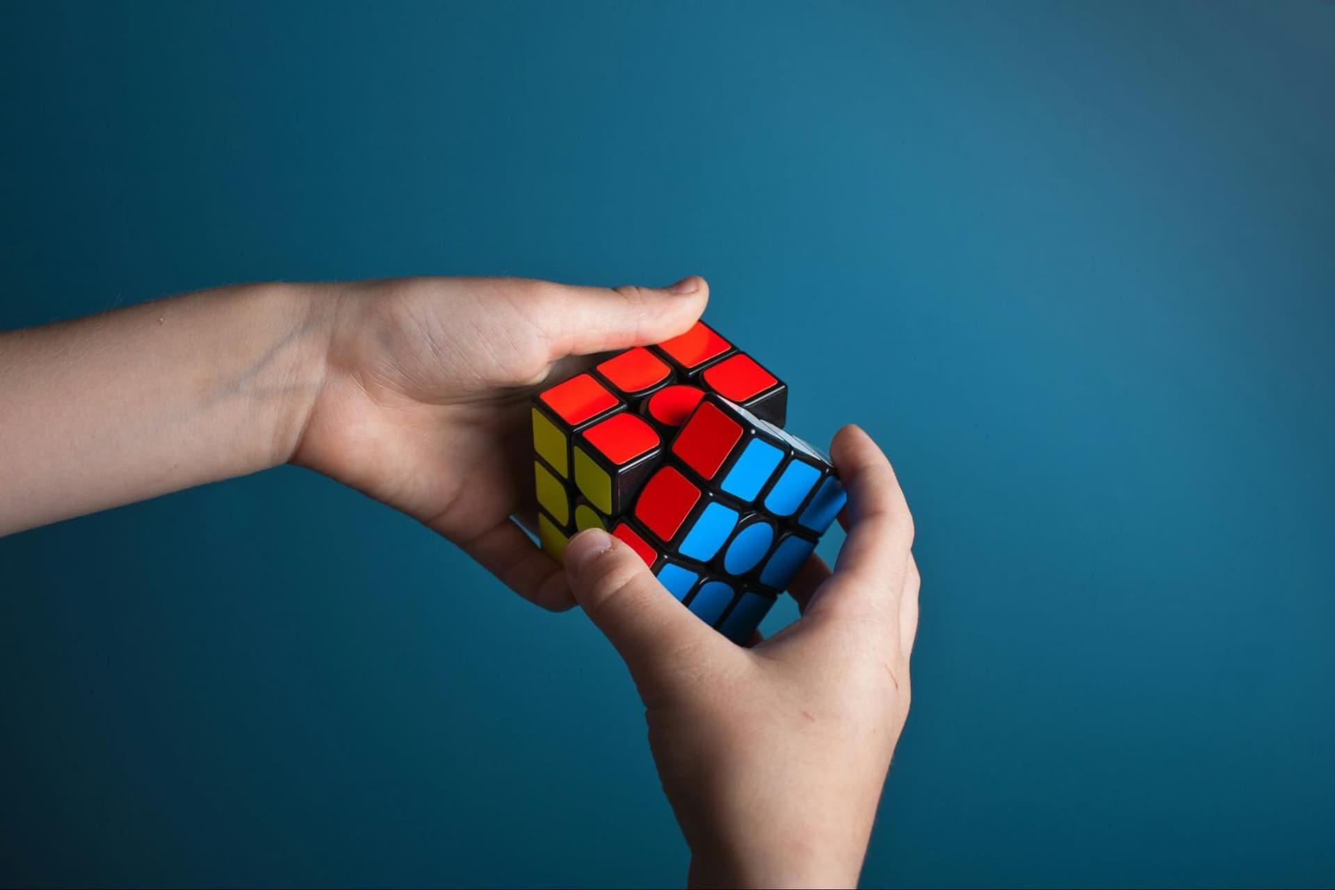 A close-up shot of hands manipulating a Rubik’s cube, showing the puzzle mid-solve