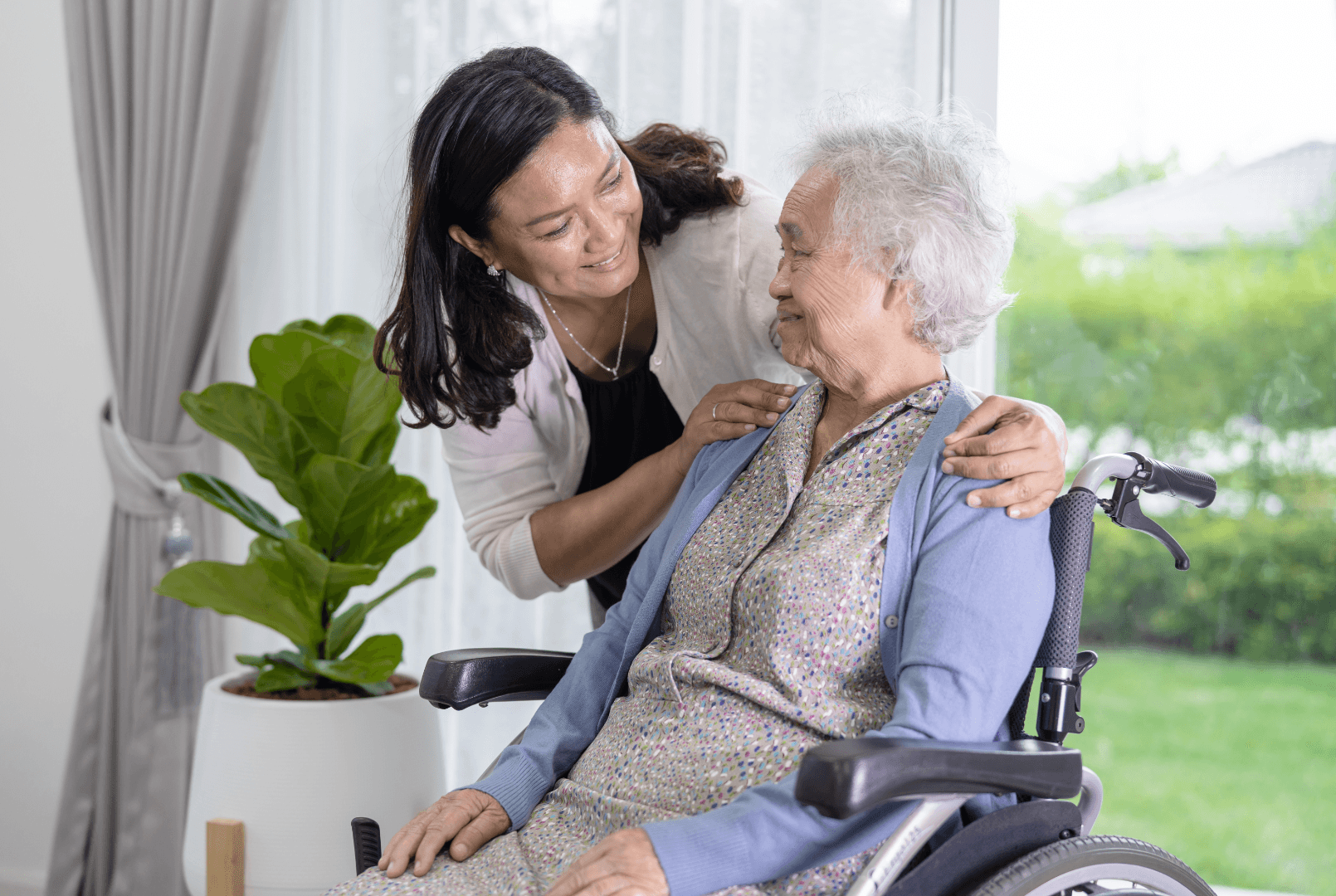 A woman speaks with an elderly woman seated in a wheelchair