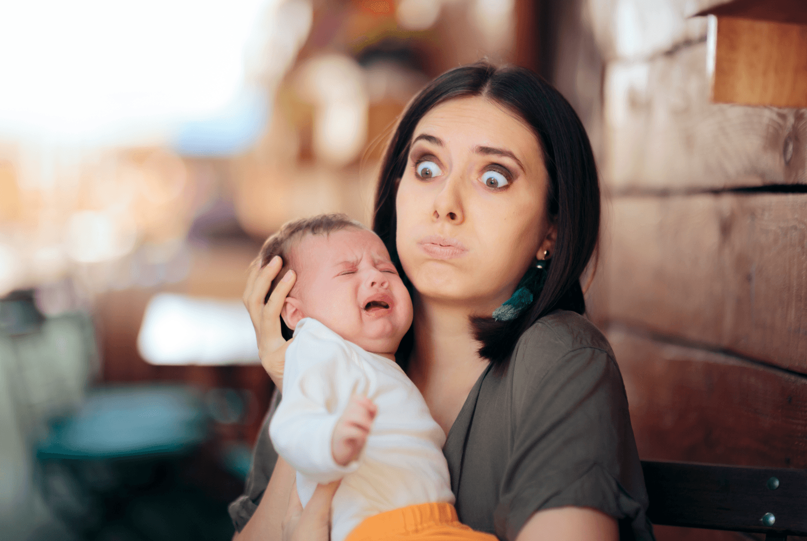 A woman holding a crying baby with a confused expression on her face