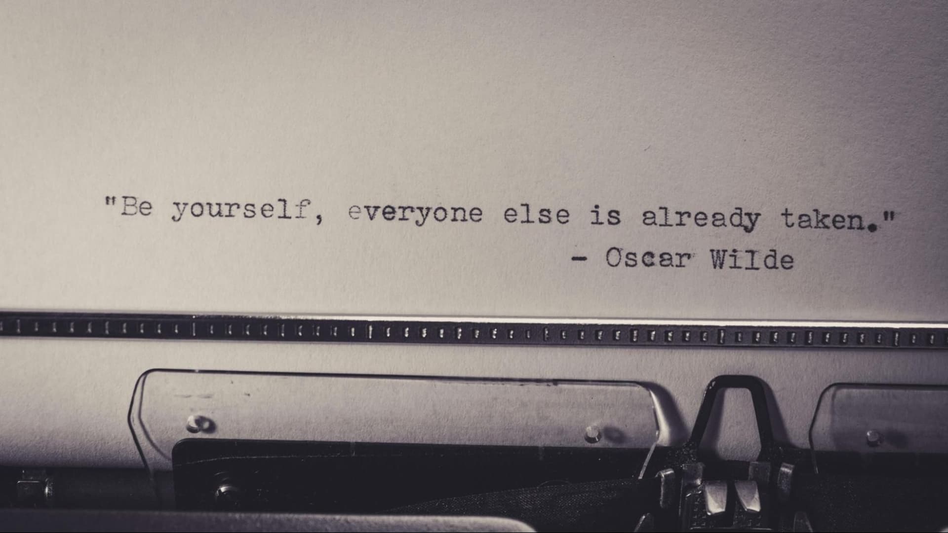 A sheet of paper in a typewriter with the quote “Be yourself, everyone else is already taken.”