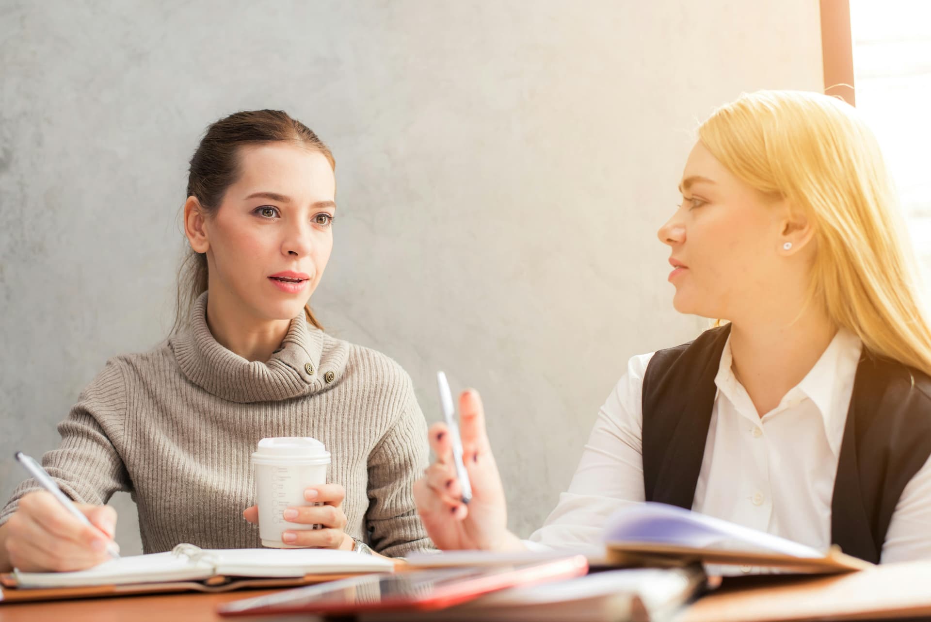 Two women standing closely and talking, appearing engaged in a meaningful conversation
