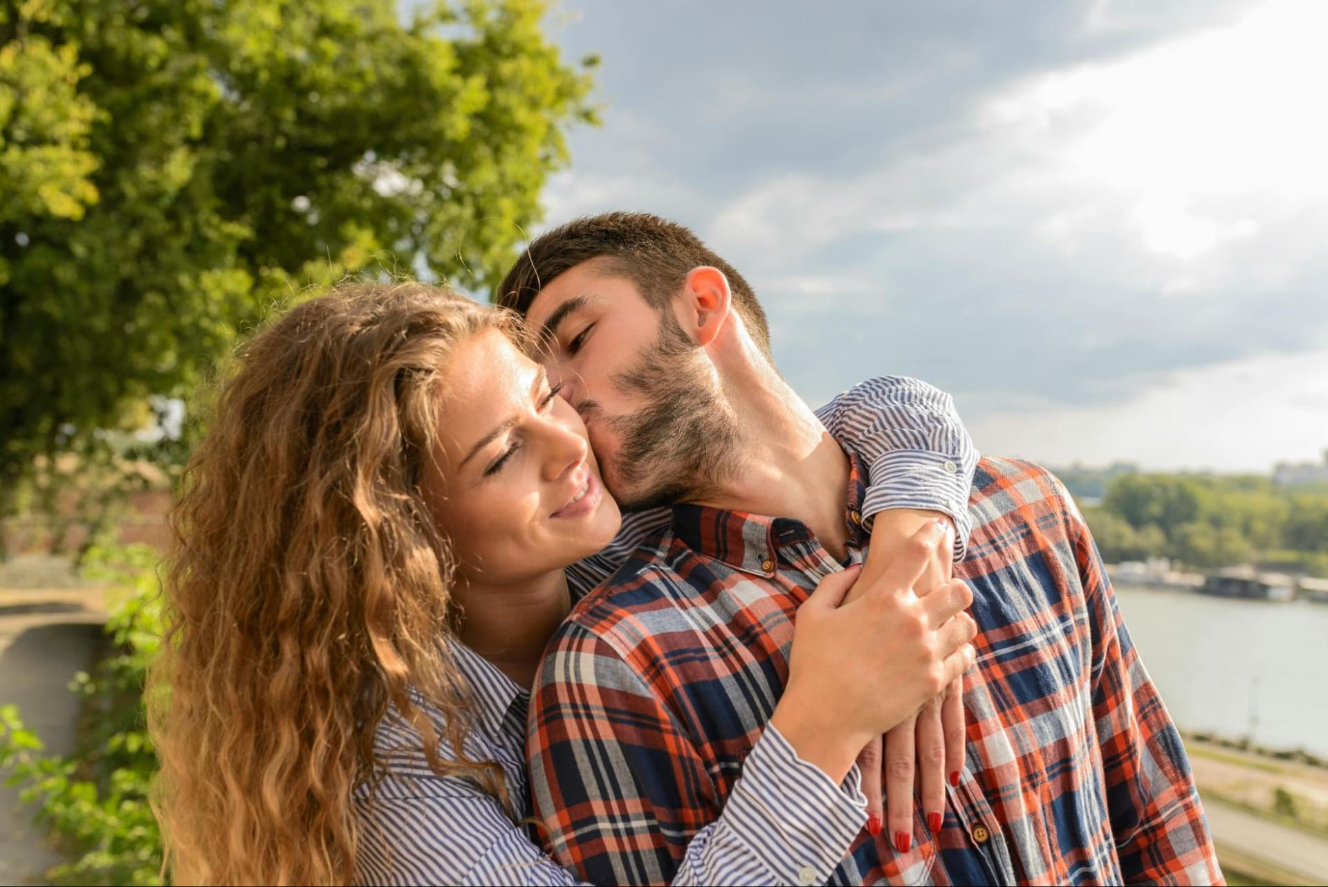 A man kissing a woman on the cheek while she embraces him