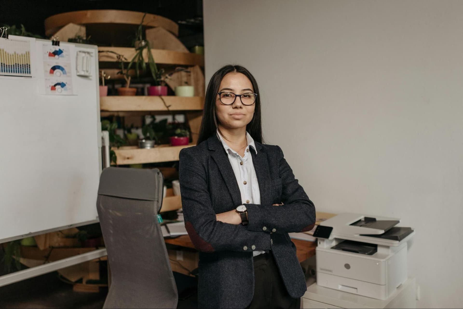 A woman in a suit and glasses standing in an office setting