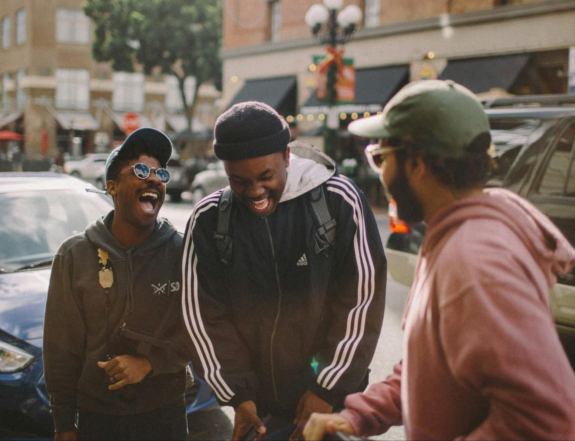 Three friends laughing together in a cheerful outdoor setting