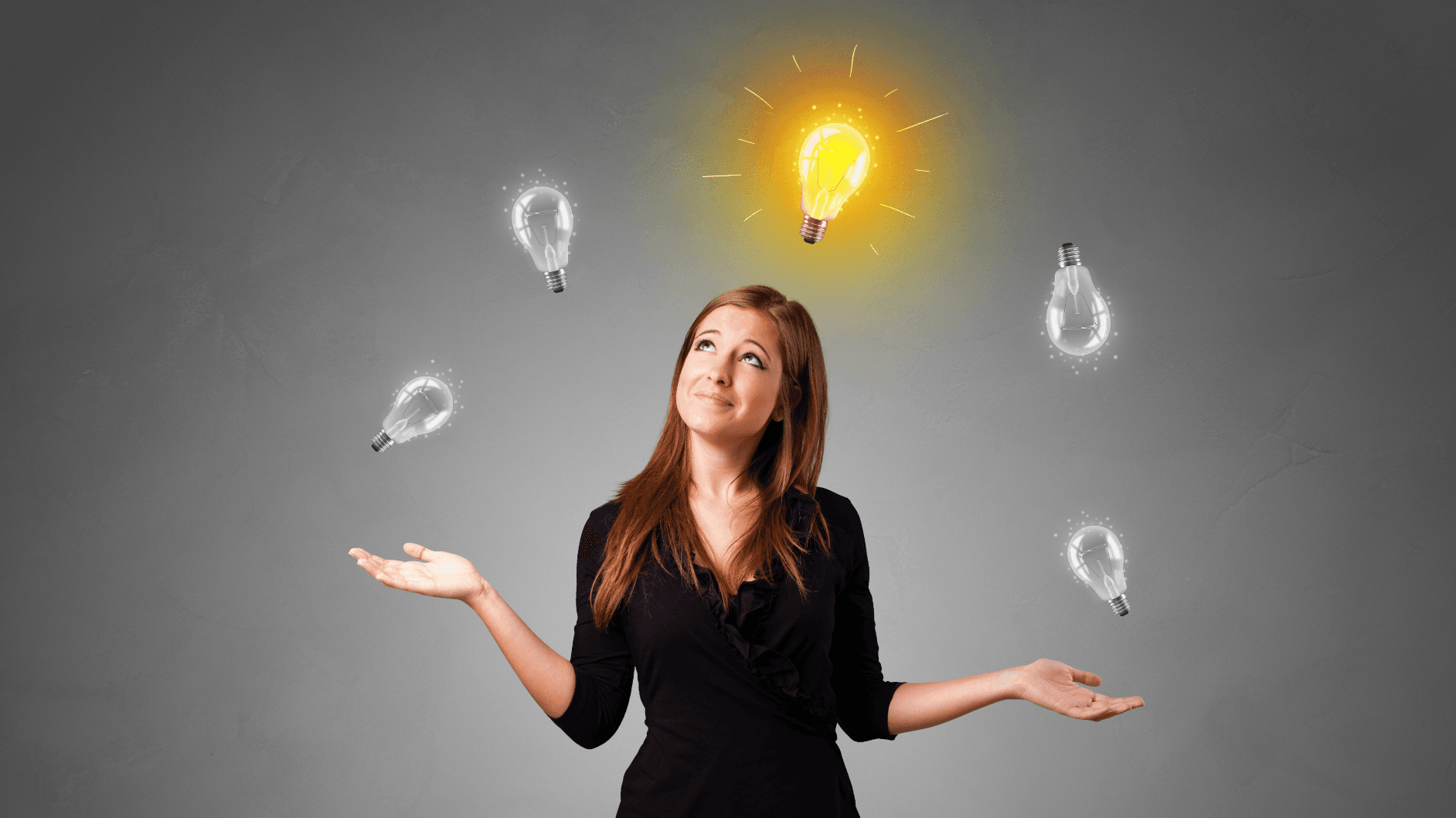 A woman juggling light bulbs, with one of them lit