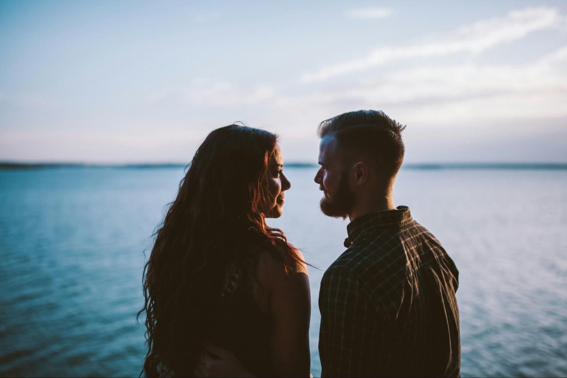 a couple looking at each other by a lake